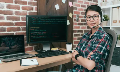 An IT specialist smiling with arms crossed while providing support for a client.