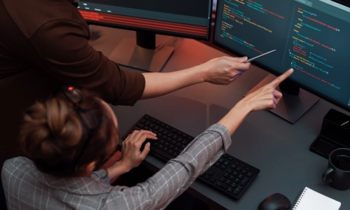 A computer specialist seated at a desk with his computer and working on Intune data migration.