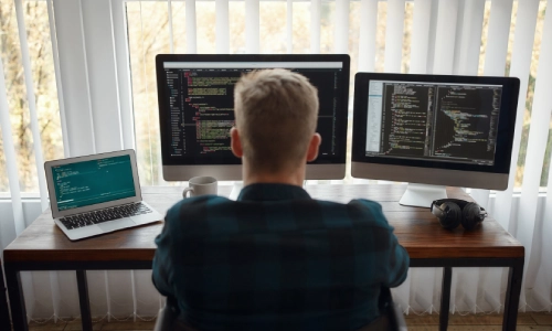 A company IT worker seated in front of a computer and working on Microsoft Intune data migration.